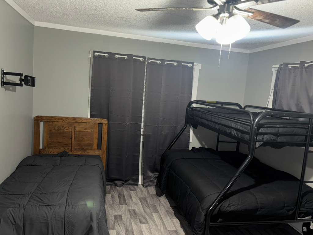 Grey bedroom featuring a wooden bed and a black metal bunk bed with dark linens.